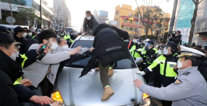 형기를 마치고 출소한 아동 성범죄자 조두순이 탑승한 관용차량이 지난해 12월 12일 오전 경기도 안산시 법무부안산준법지원센터에서 나오던 중 일부 시민과 유튜버 등에 가로막혀 있다. [연합]