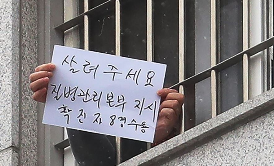 지난해 12월 29일 오후 서울 송파구 동부구치소에서 한 수용자가 확진자 과밀수용 등 불만 사항을 직접 적어 취재진을 향해 들어 보이는 모습. [연합]