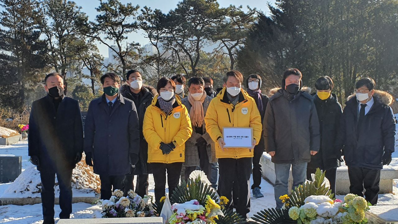 10일 정의당 지도부가 경기 남양주 모란공원묘지에 영면한 고(故) 노회찬 전 의원의 묘역을 참배한 가운데 김종철(가운데) 정의당 대표가 지난 8일 국회 본회의를 통과한 중대재해법 법률안을 들어 보이고 있다. [정의당 제공]
