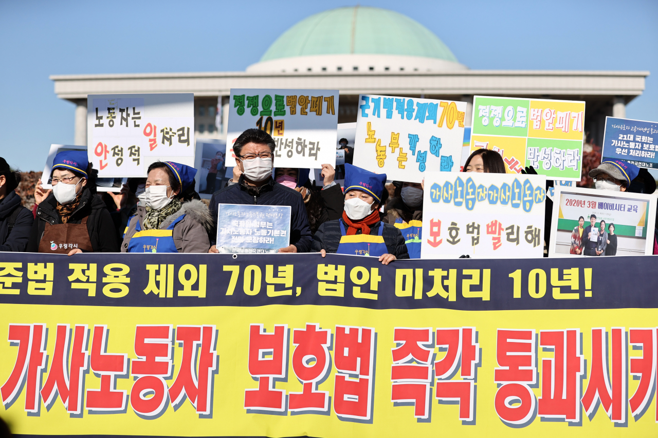 지난해 11월 4일 오전 국회 앞에서 열린 가사근로자 고용개선에 관한 법 통과 촉구 기자회견에서 한국가사노동자협회 등 참석자들이 관련 내용이 적힌 손 피켓을 들고 있다. [연합]