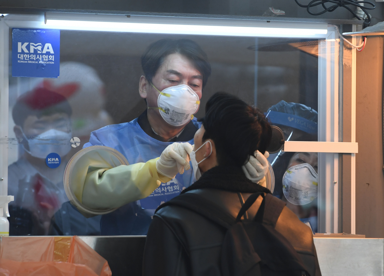 국민의당 안철수 대표가 15일 서울광장에 마련된 임시 선별검사소에서 의료 자원봉사에 나서 검체를 채취하고 있다. [연합]