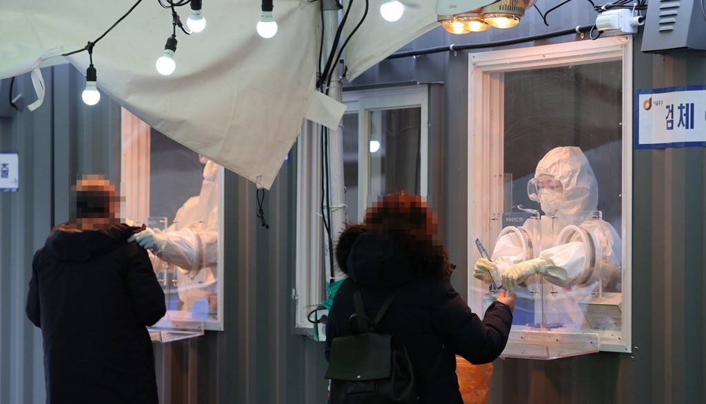 Medical workers collect specimens for coronavirus testing at a makeshift clinic in front of Seoul Station on Jan. 11, 2021. (Yonhap)