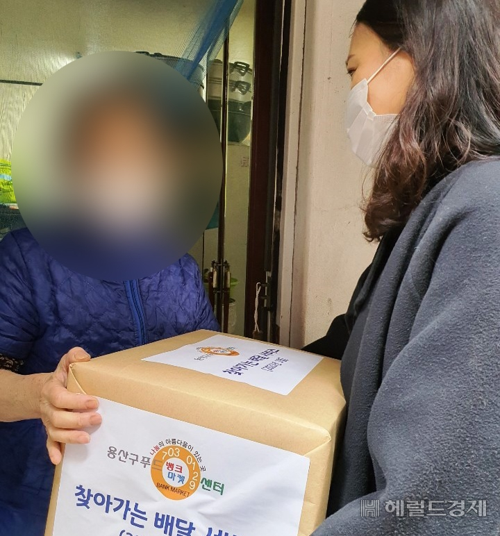 용산구 푸드뱅크마켓센터 직원이 코로나19로 외출이 어려운 이용자에게 물품을 전달하고 있다. [용산구 제공]