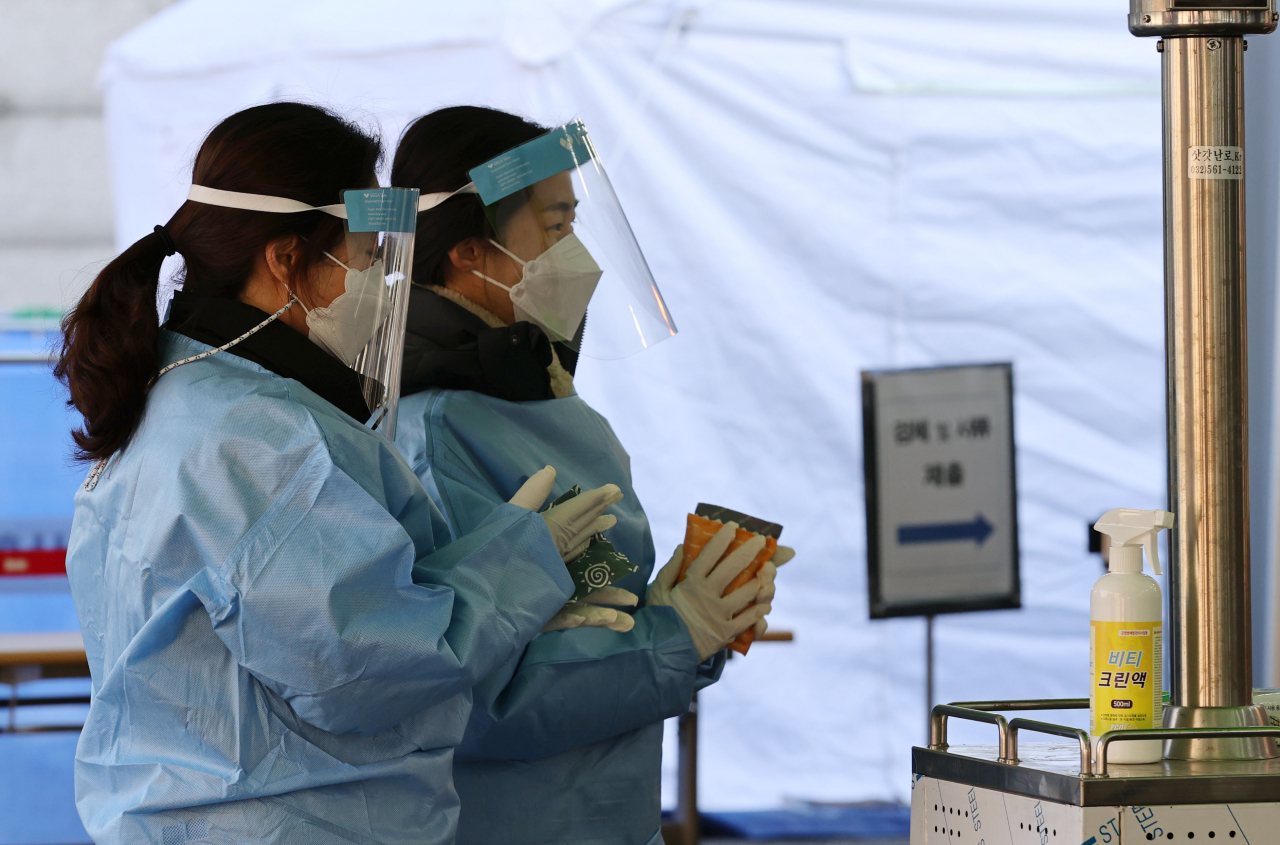 오는 20일 국내에서 신종 코로나바이러스 감염증(코로나19) 첫 확진자가 나온 지 꼭 1년째가 되는 가운데 19일 오전 서울역 광장에 마련된 임시 선별진료소에서 의료진이 핫팩으로 추위를 녹이고 있다. 연합뉴스