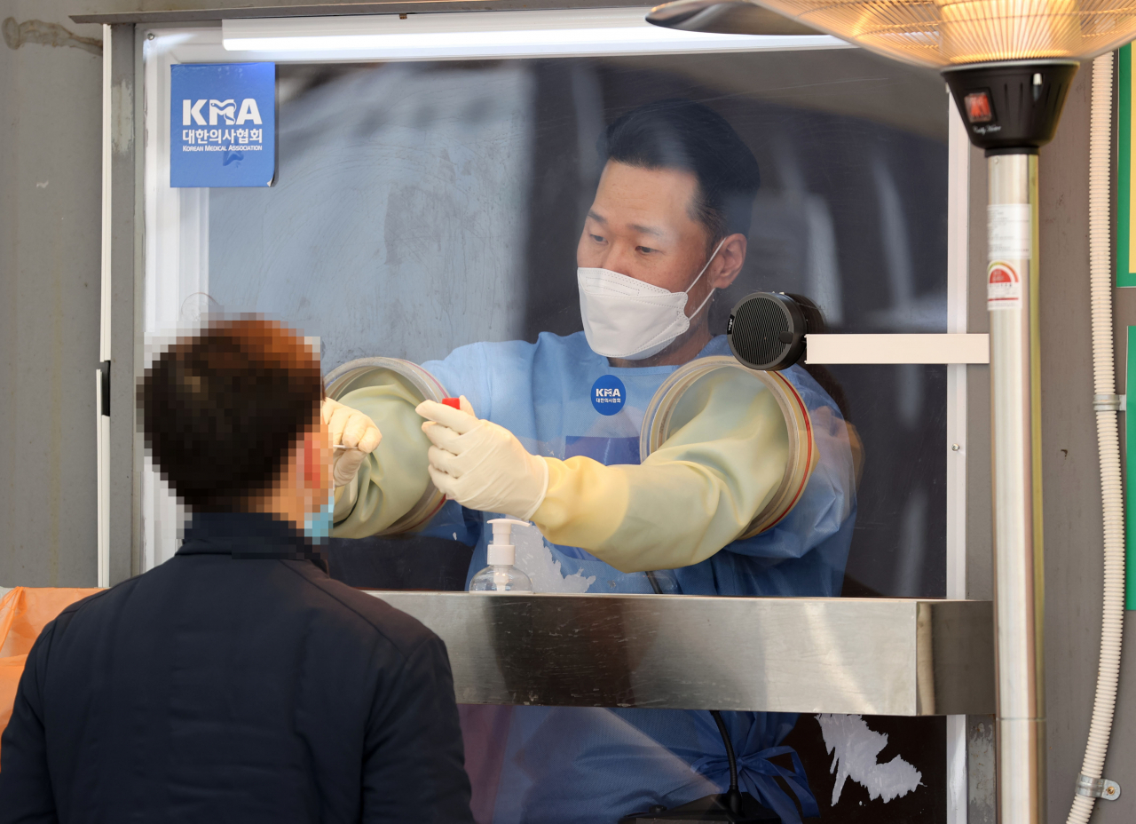 오는 21일 국내에서 '코로나19' 첫 확진자가 나온 지 꼭 1년째가 되는 가운데 19일 오후 서울광장에 마련된 임시 선별진료소에서 의료진이 검체를 채취하고 있다. [연합]