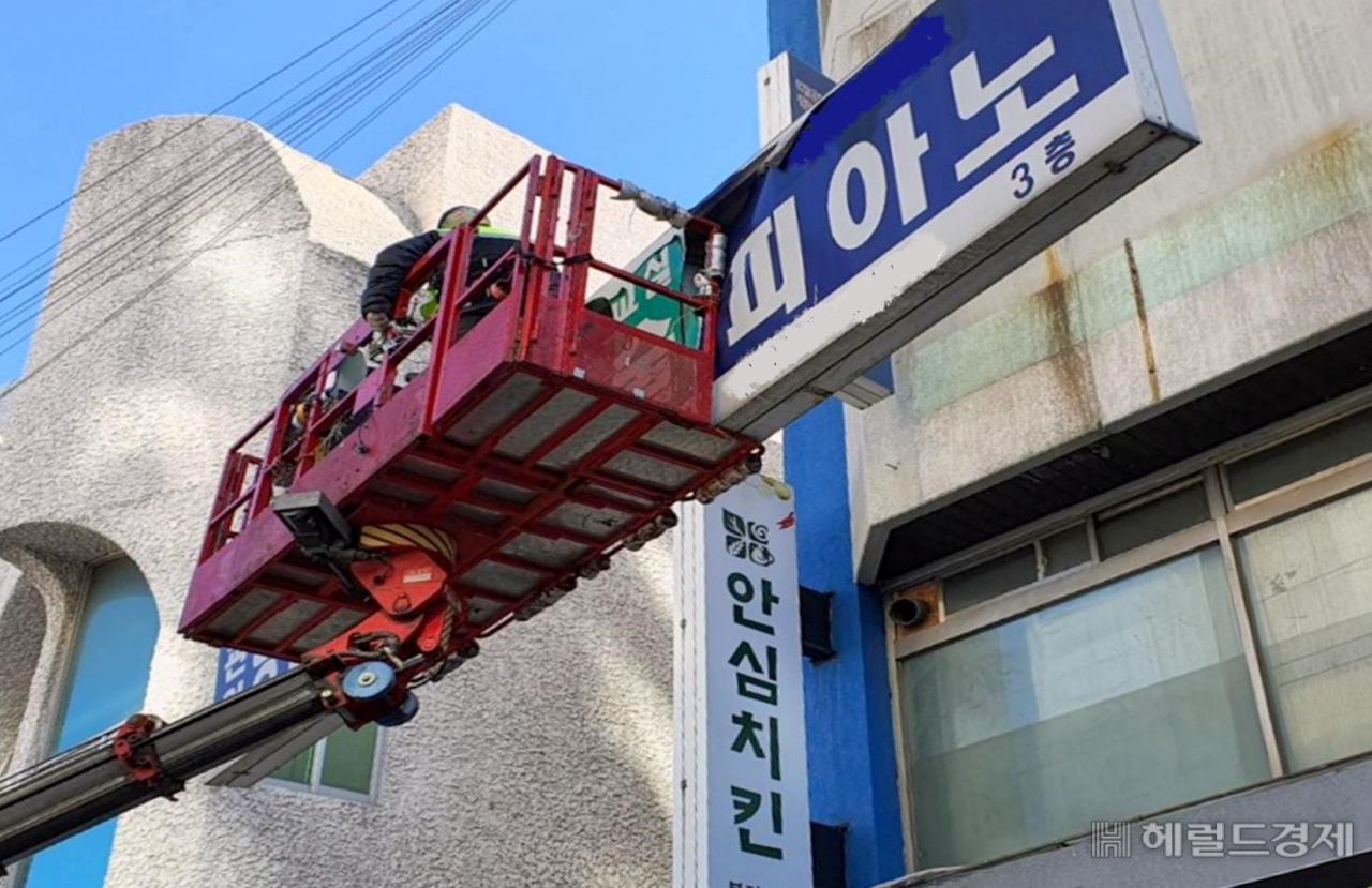 건물 외벽에서 주인없는 간판을 떼내고 있다. [서대문구 제공]