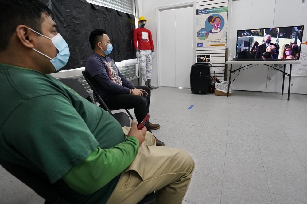 Workers Justice Project Director Gonzalo Cruz, left, and organizer Juan Carlos Romero watch President Joe Biden's presidential inauguration on TV from the Workers Justice Center, Wednesday, in the Sunset Park neighborhood of Brooklyn in New York. The Workers Justice Project is a Brooklyn based non-profit that helps immigrants. (AP-Yonhap)