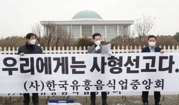 한국유흥음식업중앙회 회원 등이 지난 21일 오후 국회 앞에서 ‘유흥주점 집합금지 중단조치 촉구 기자회견’을 하고 있다. [연합]
