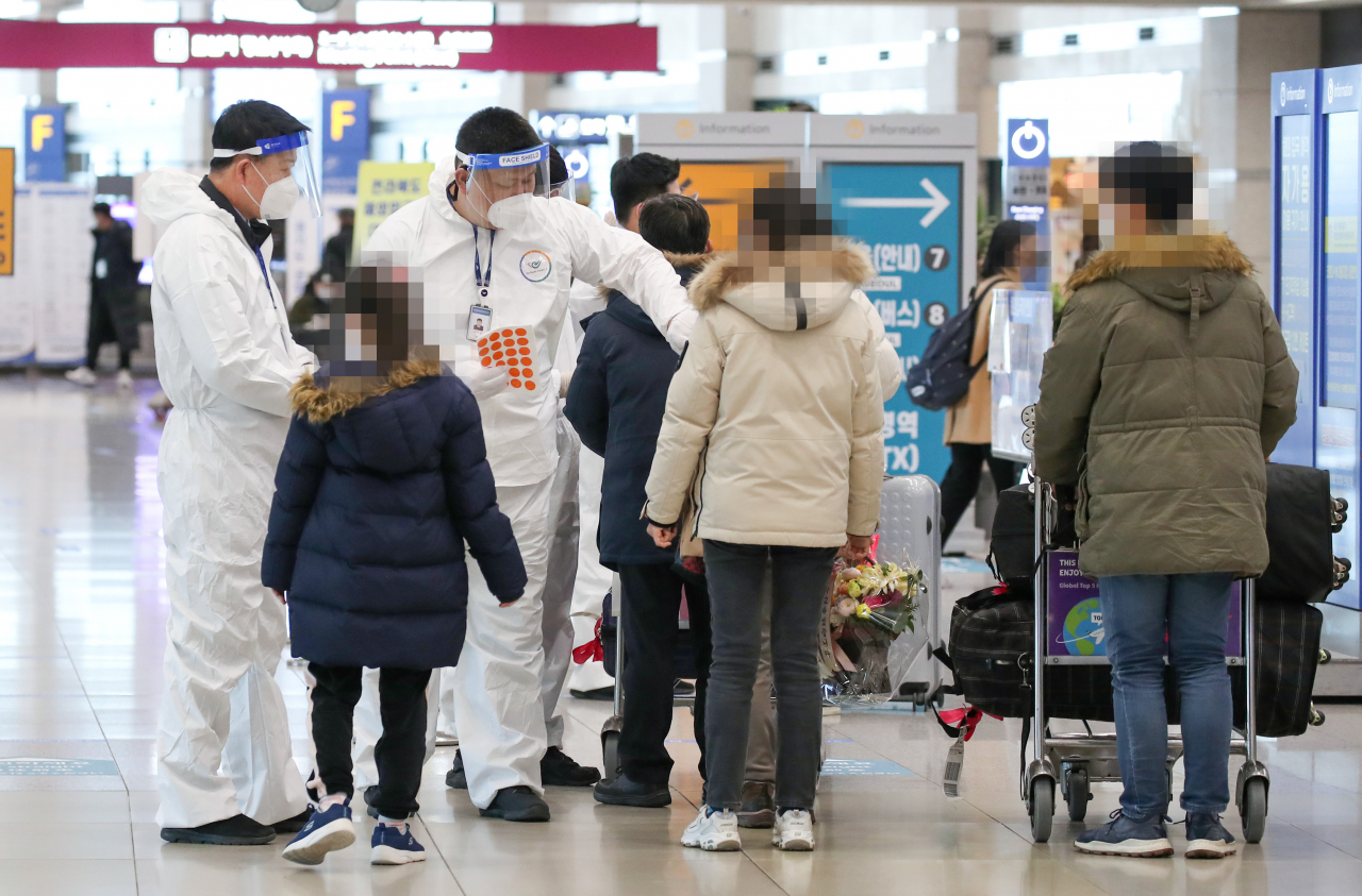 19일 오후 인천국제공항 제1터미널 입국장에서 해외입국자들이 방역관계자로부터 안내를 받고 있다. [연합]