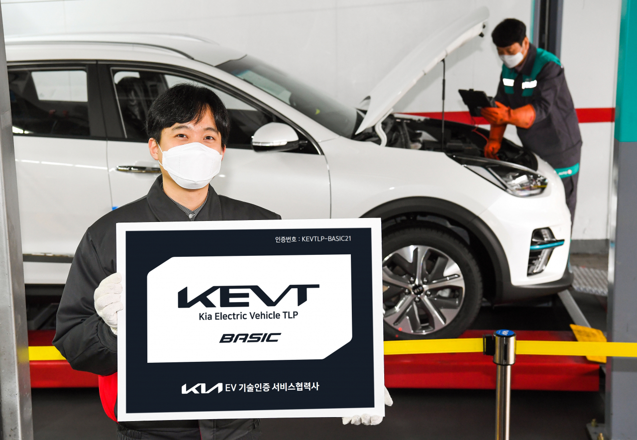 기아 오토큐 정비 엔지니어가 ‘KEVT 베이직’ 인증 현판을 선보이고 있다. 인증 현판이 있는 오토큐에서는 전문적인 전기차 정비를 받을 수 있다. [기아 제공]