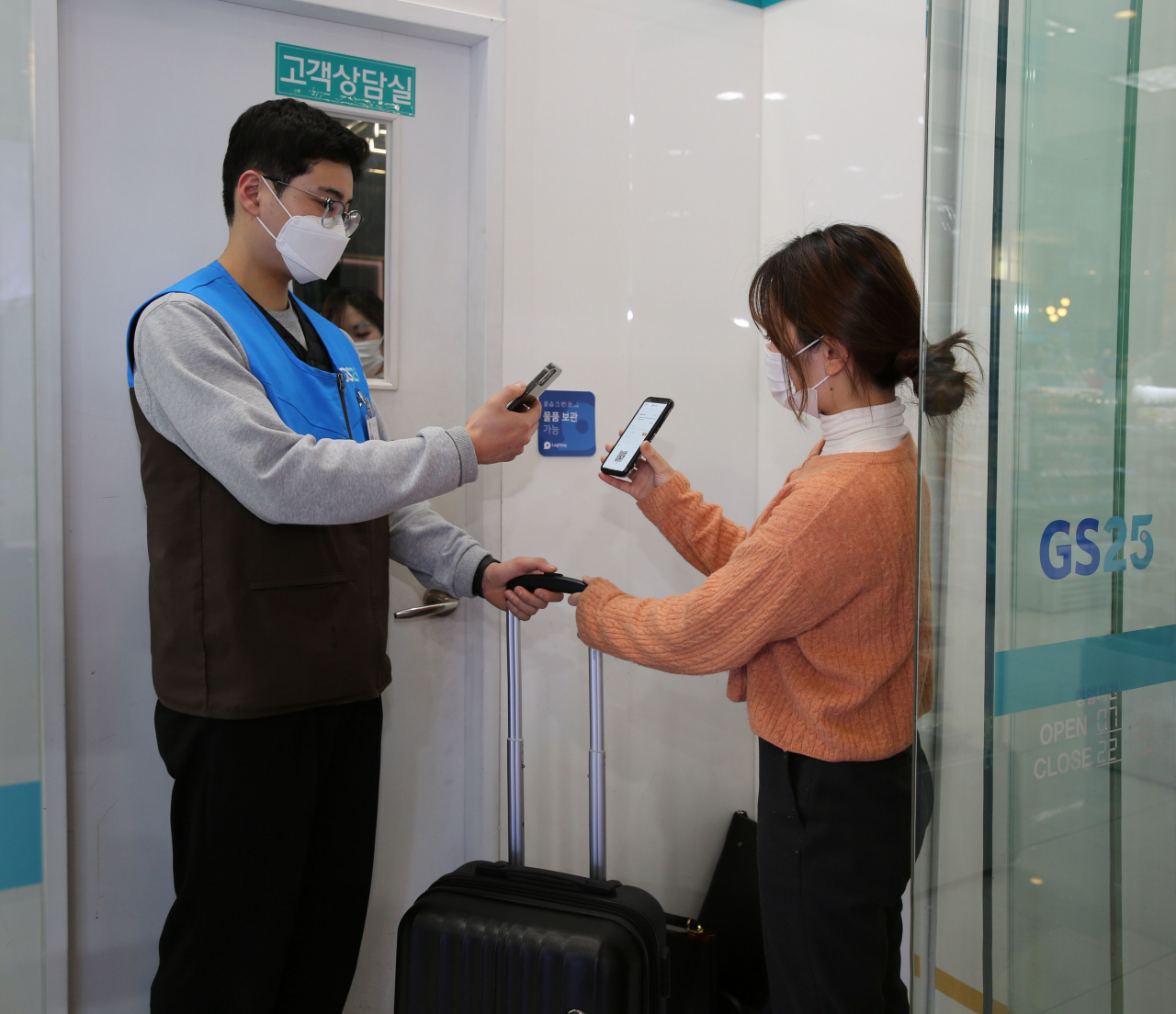 고객이 GS25점포에 여행용 캐리어를 맡기고 있다.[GS25 제공]