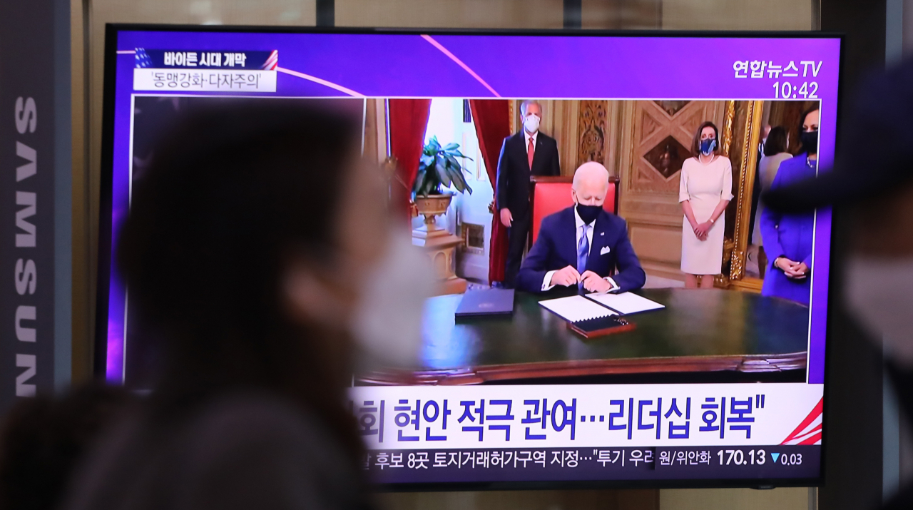 지난 21일 서울역에서 시민들이 조 바이든 미국 대통령 취임 관련 뉴스를 보고 있다. [연합뉴스]