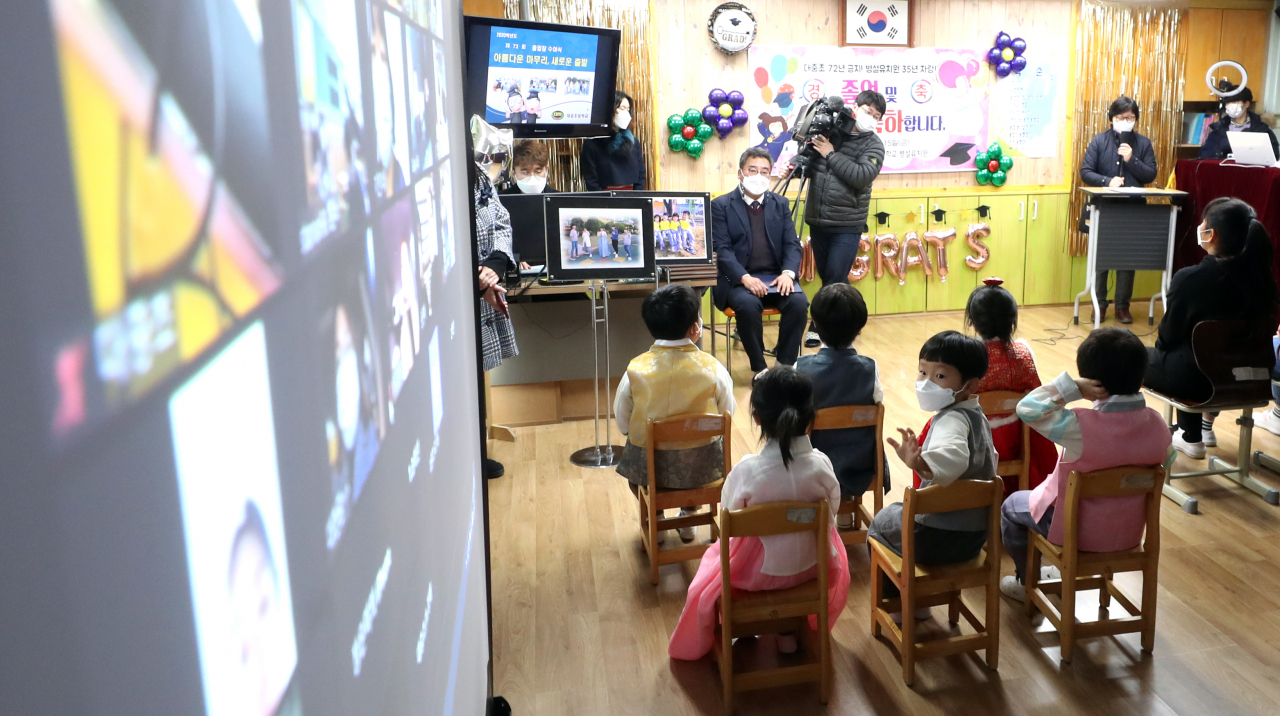 지난 15일 경남 김해시 대중초등학교에서 열린 초교·병설 유치원 비대면 졸업 및 수료식에서 유치원 수료생이 교실 뒤에 설치된 모니터를 통해 가족을 바라보고 있다. [연합]