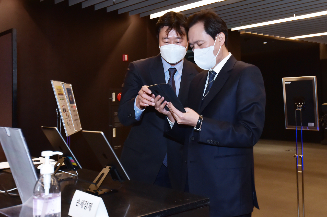 4·7 서울시장 보궐선거 출마 선언을 한 더불어민주당 우상호 의원(오른쪽)이 26일 서울 여의도 글래드호텔에서 열린 '경기도 기본주택 토론회'에 참석, 큐알(QR)코드 인증을 하고 있다. [연합]