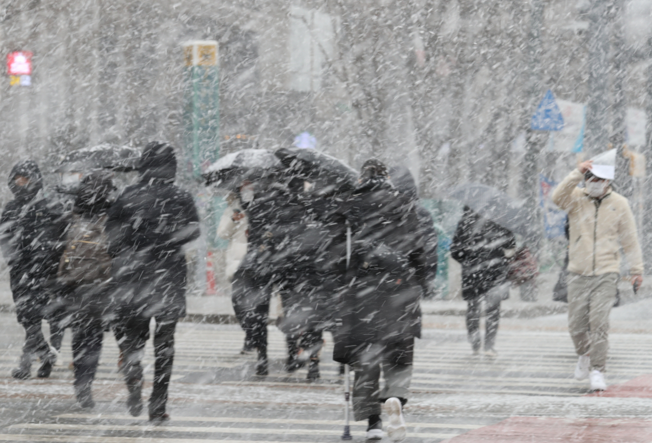 서울과 경기 북부에 대설주의보가 내려진 28일 서울 광화문 네거리 인근에서 시민들이 눈을 맞으며 걸어가고 있다.[연합]