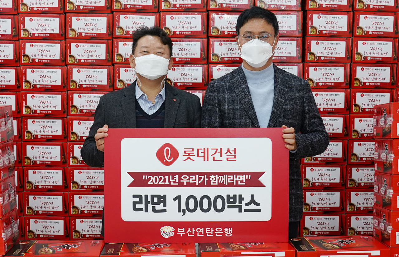 김재권 롯데건설 영남지사장(왼쪽)과 강정칠 부산연탄은행 대표가 사랑의 라면 나눔 활동을 기념해 촬영중이다.[롯데건설 제공]