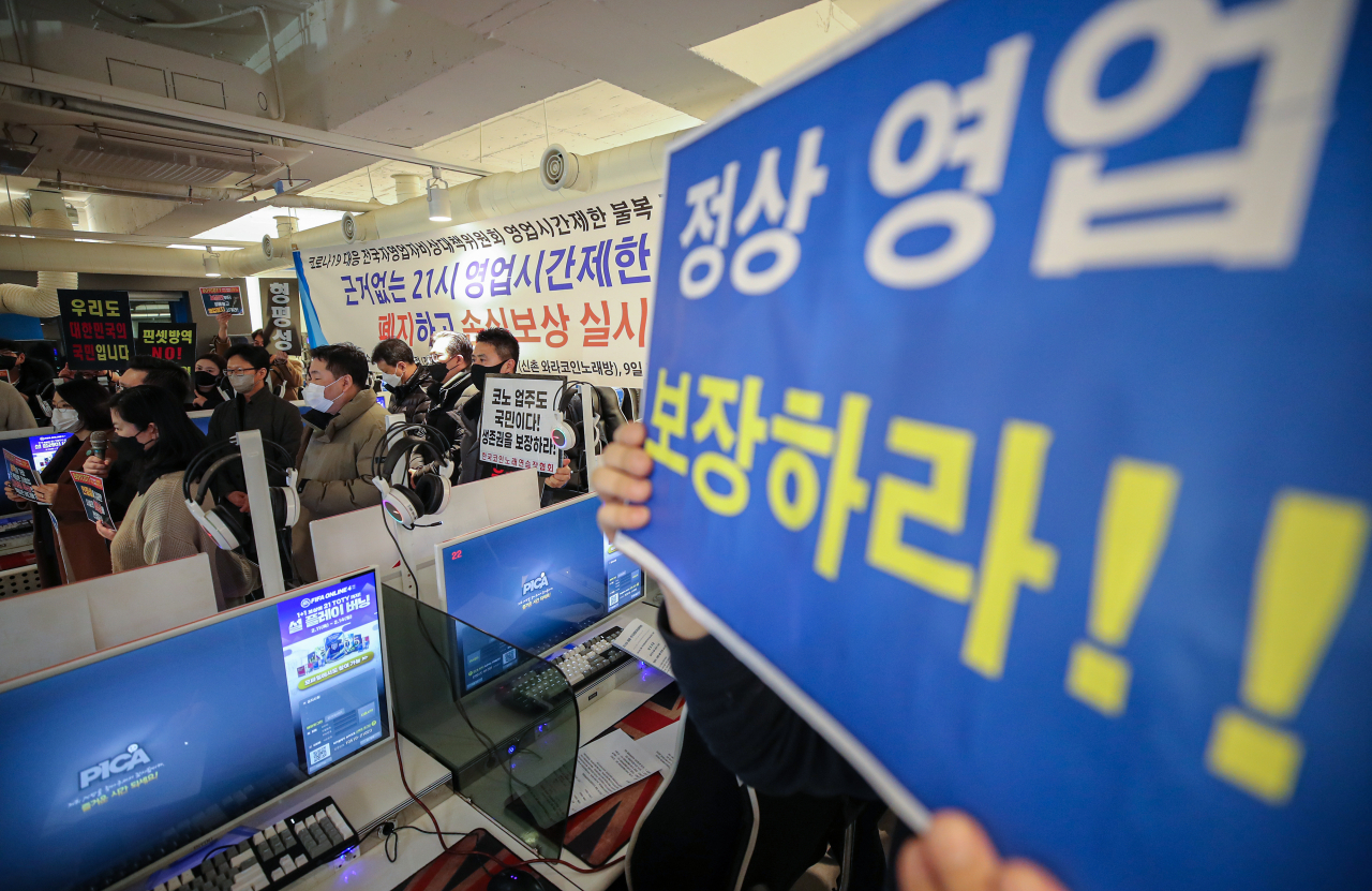 8일 자정 서울 강서구의 한 피시방에서 코로나19 대응 전국자영업자 비상대책위 주최로 열린 방역기준 불복 개점 시위에서 참석자들이 정상 영업을 촉구하는 손팻말을 들고 있다. 이날 시위에서 피시방 업주들은 방역 당국의 획일적인 영업시간 제한 폐지, 형평성 있는 방역기준 조정과 대책 마련을 촉구했다. [연합]