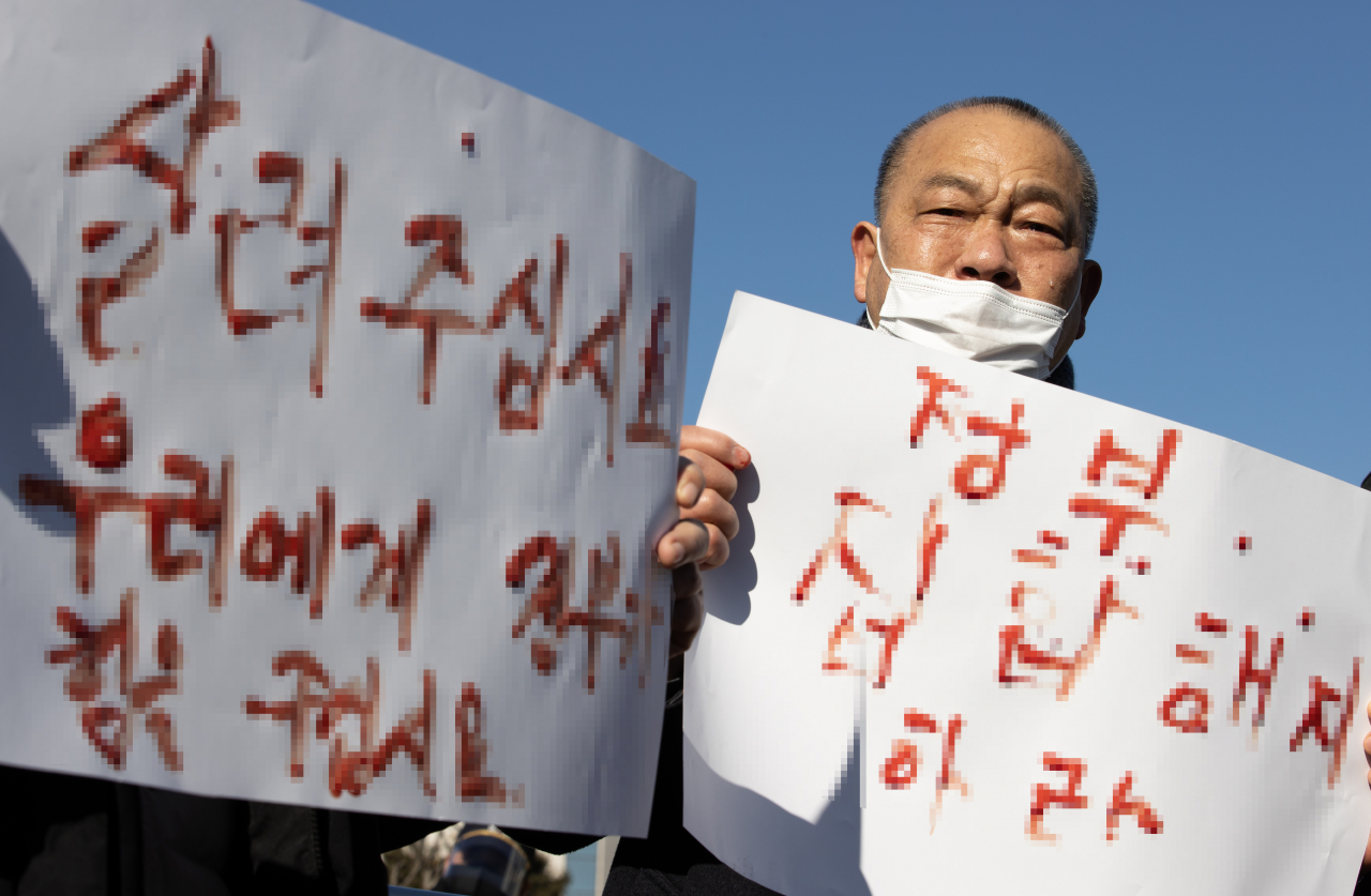 지난 8일 오후 국회 앞에서 열린 '형평성 없는 장기간 집합금지 업종 해제 및 손실보상 기자회견'에서 한국유흥음식업중앙회 등 참가자가 보상 등을 촉구하는 내용의 혈서를 들어보이며 눈물을 흘리고 있다. [연합]