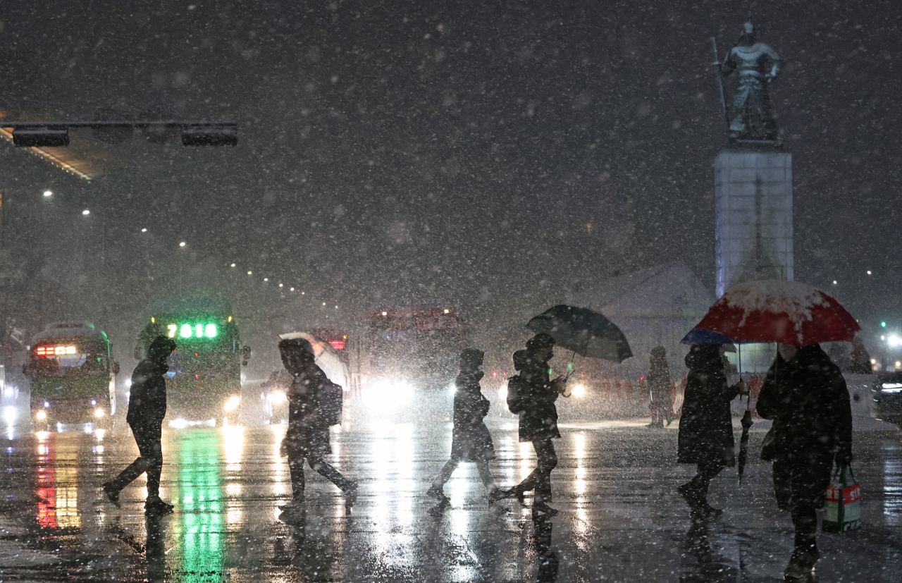 Evening commuters cross a road in Gwanghwamun, central Seoul, on a February day. (Yonhap)
