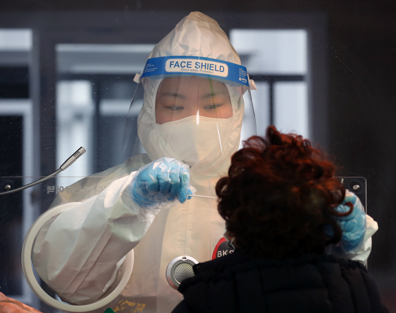 지난 19일 오후 서울 중구 서울역 광장에 설치된 코로나19 임시 선별 검사소에서 의료진이 시민의 검체를 채취하고 있다. [연합]