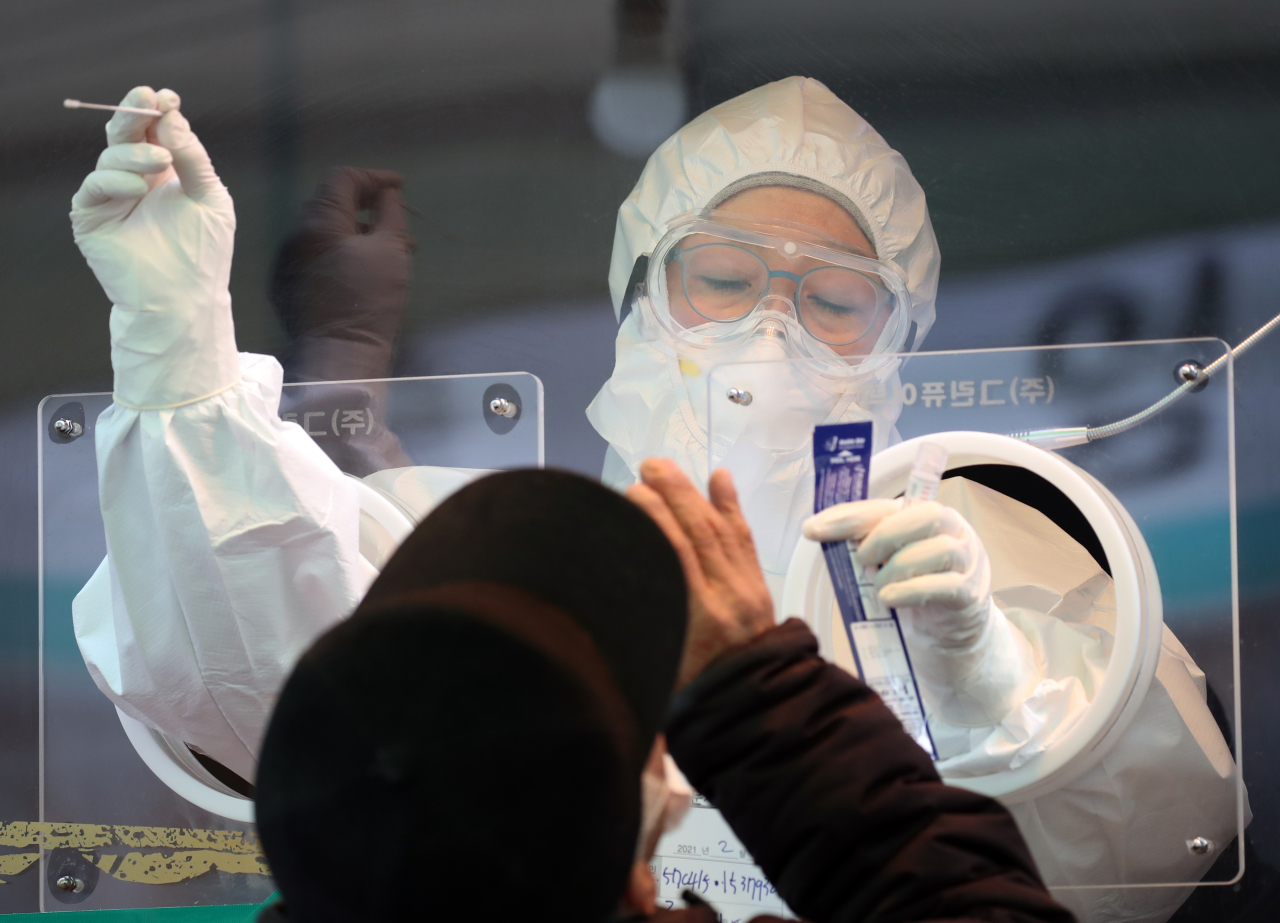A health care worker collects a nasal swab sample to test for COVID-19