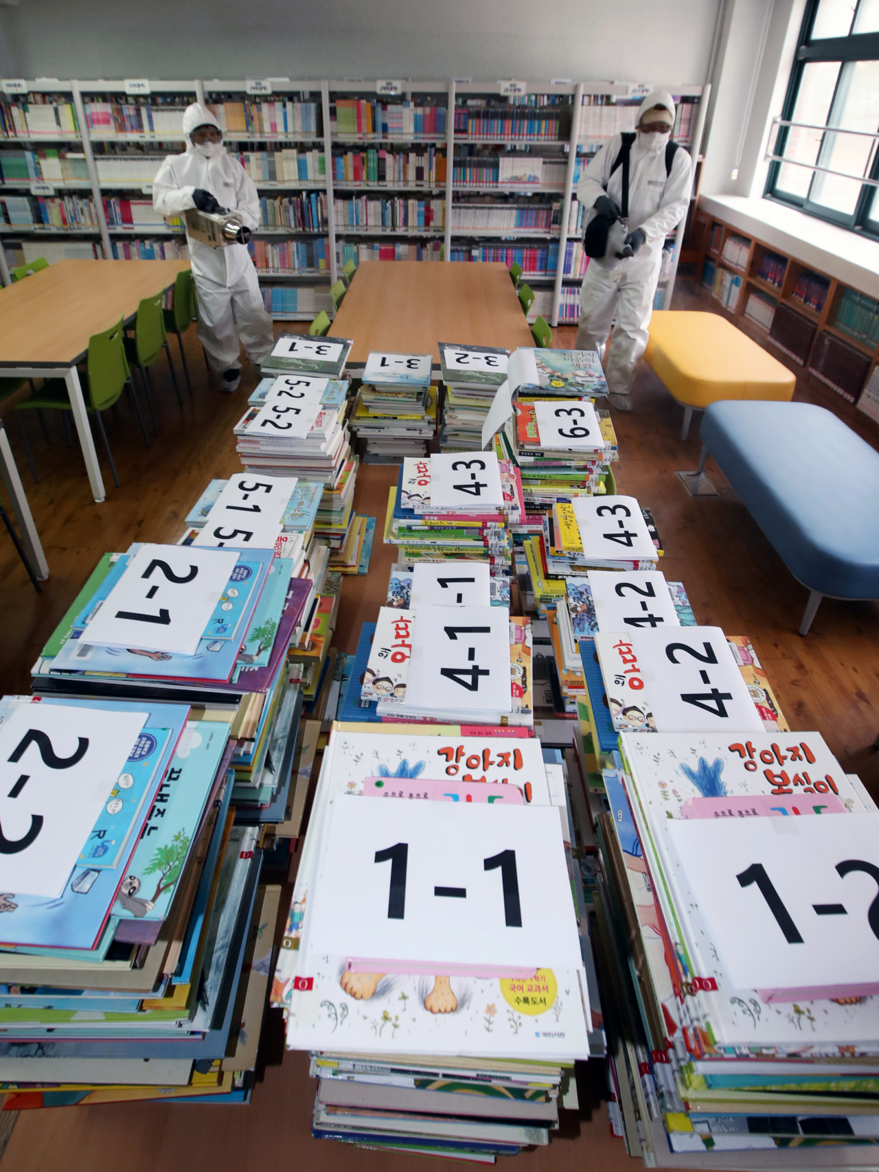 2021학년도 새 학기 개학을 엿새 앞둔 지난 24일 광주 서구 금당초등학교에서 방역요원이 신종 코로나바이러스 감염증(코로나19) 예방을 위해 도서실을 방역하고 있다. [연합]