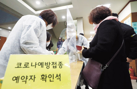 신종 코로나바이러스 감염증(코로나19) 백신 접종 시작일인 26일 오전 인천시 부평구 부평구보건소에서 한 시민이 백신 접종 예약을 확인하고 있다. 오른쪽은 코로나19 백신 예방접종 내역 확인서 [연합]