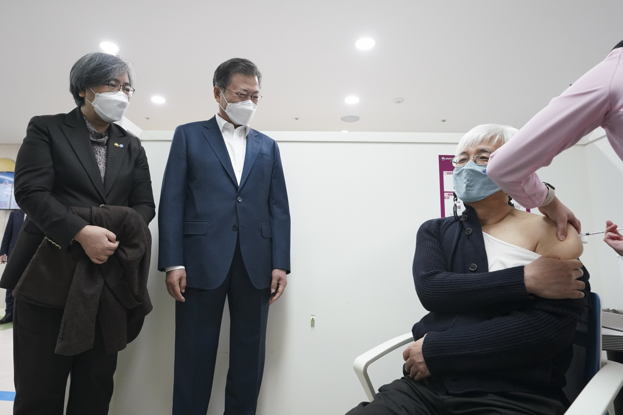 문재인 대통령이 26일 서울 마포구보건소를 방문, 재활시설 종사자인 김윤태 의사(푸르메 넥슨어린이 재활병원)가 아스트라제네카(AZ) 백신을 접종받는 모습을 지켜보고 있다. [연합]