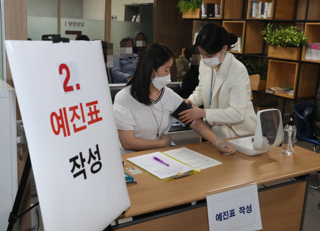 지난 26일 서울 관악구보건소 2층에서 신종 코로나바이러스 감염증(코로나19) 백신접종이 시작됐다. 보건소에서 대기 중인 백신접종 대상자가 예진표 작성 후 혈압체크를 하고 있다. [연합]