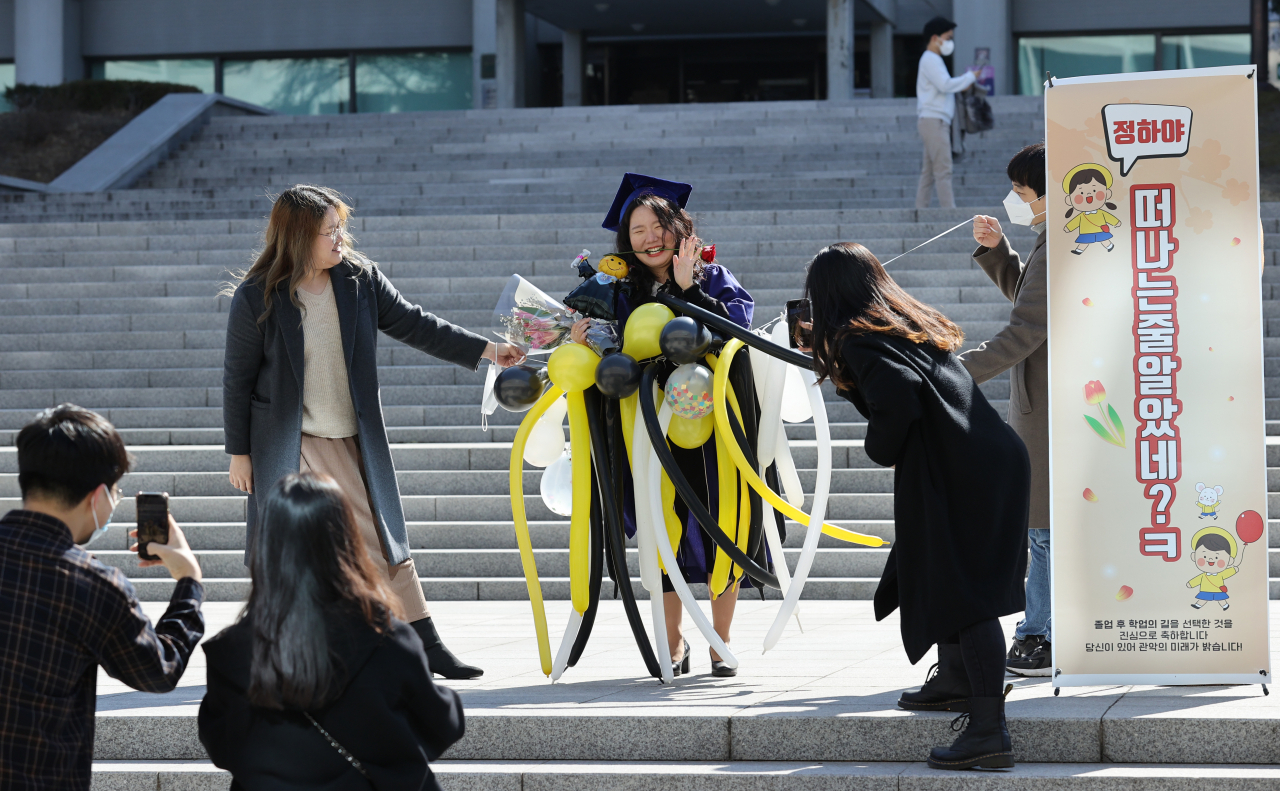 26일 서울 관악구 서울대 중앙도서관 앞에서 한 졸업생이 친구들이 준비한 배너, 풍선과 함께 기념사진을 찍고 있다.(사진은 기사 내용과 관련없음) [연합]