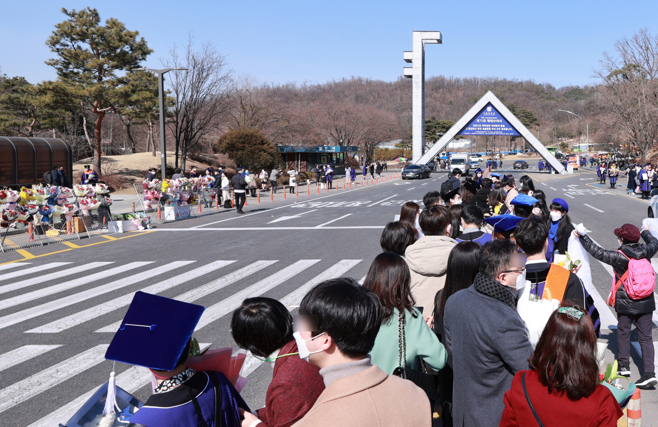 26일 서울 관악구 서울대에서 이날 학위를 받은 졸업생과 가족들이 학교 정문을 배경으로 기념사진을 찍기 위해 줄지어 차례를 기다리고 있다. [연합]