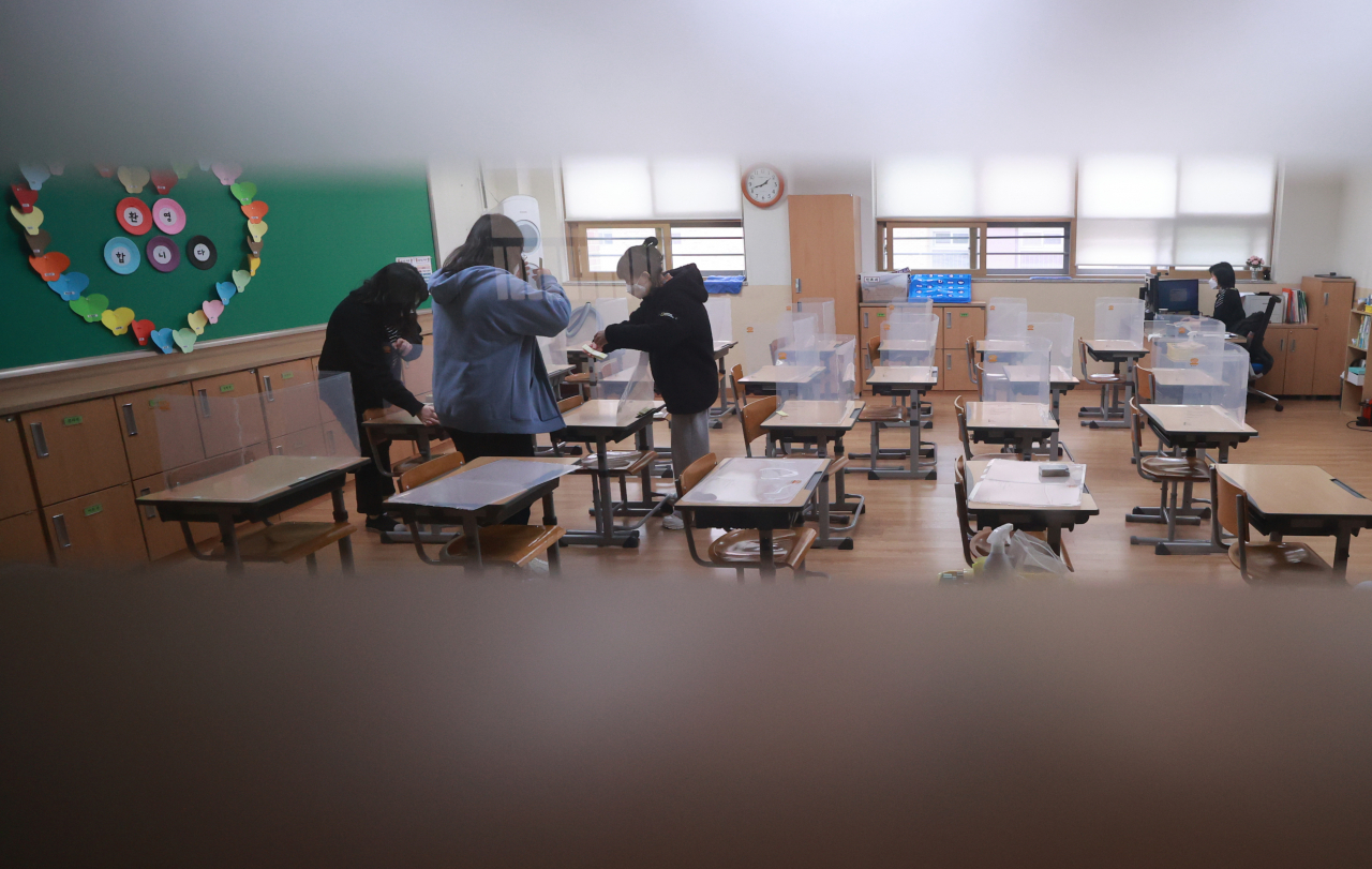 3월 새학기 개학을 앞두고 25일 오후 서울 서초구 언남초등학교에서 교실 책상 가림막을 설치하고 책상과 가림막을 소독액으로 닦는 방역 작업이 실시되고 있다. 이 학교는 새 학기 첫 주 학생들의 학교 생활 적응을 위해 시간대를 달리해 전교생이 순차 등교 수업을 실시한다. [연합]