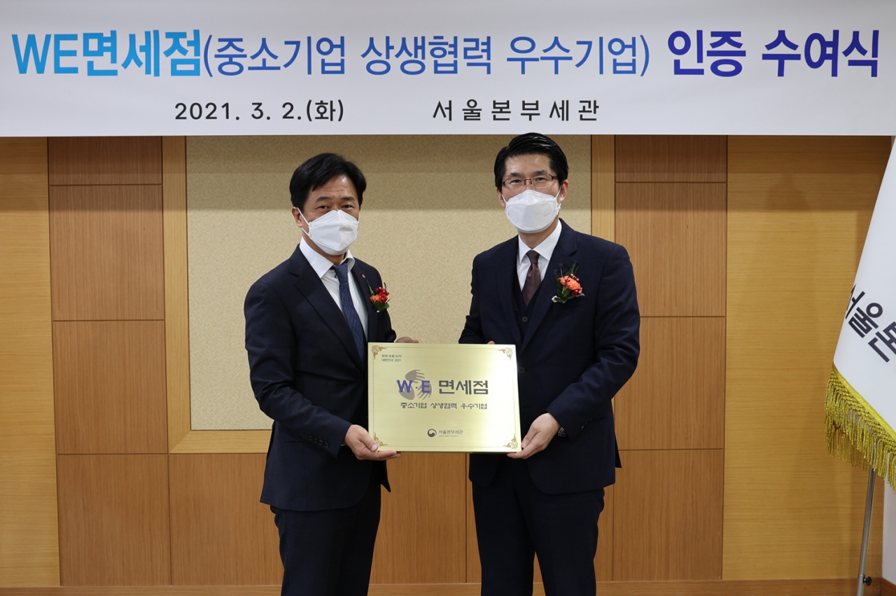 이갑 롯데면세점 대표이사(사진 왼쪽)가 지난 2일 서울 강남구 서울본부세관에서 롯데면세점 명동본점의 상생 협력에 대한 공로를 인정받아 'W.E 면세점' 인증패를 받은 후 기념 촬영을 하고 있다. [롯데면세점 제공]