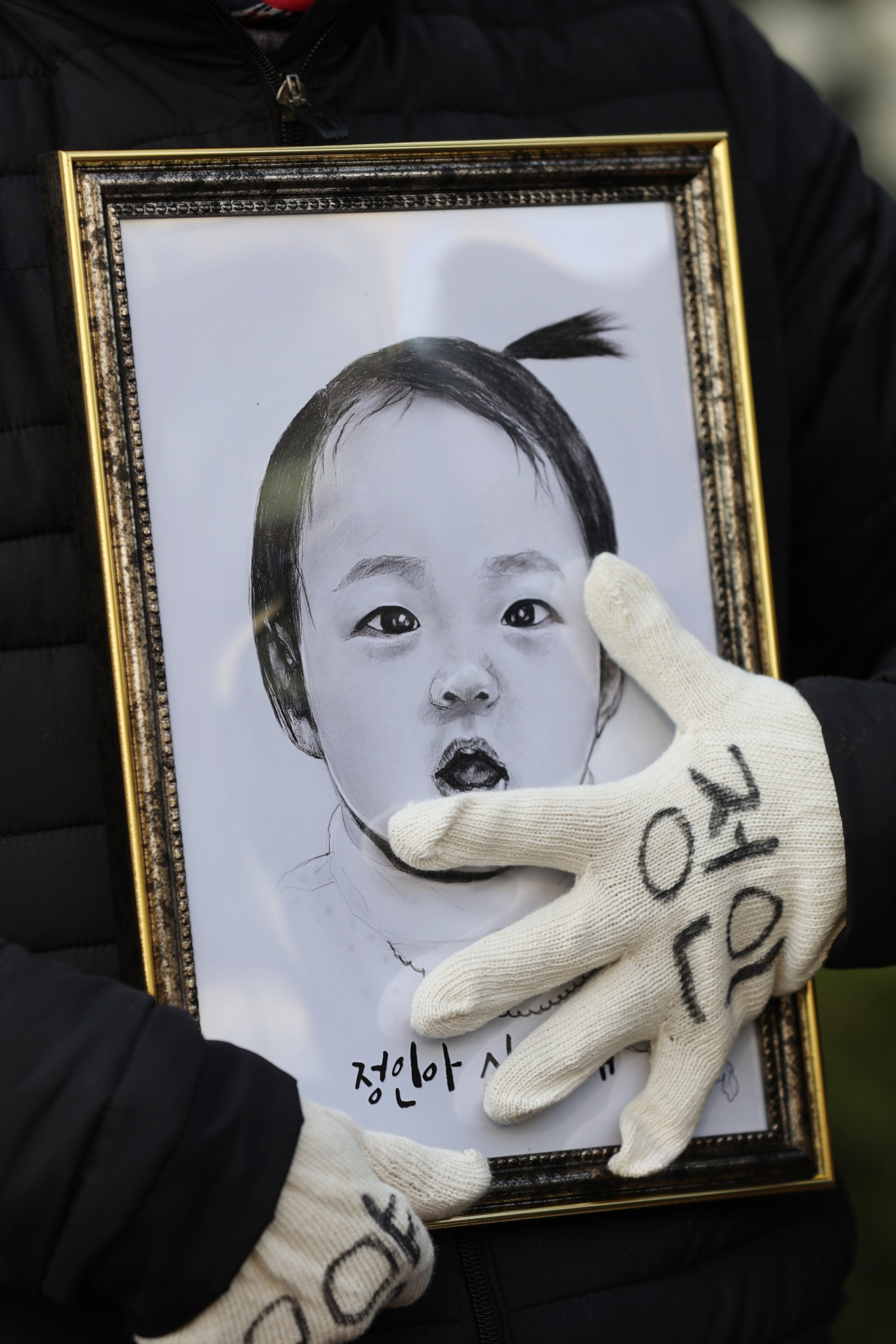 16개월 된 입양 딸 정인이를 학대해 숨지게 한 혐의를 받는 양부모의 3차 공판이 열린 이달 3일 오전 서울 양천구 서울남부지법 앞에서 한 시민이 정인이의 얼굴이 그려진 그림을 어루만지고 있다. [연합]