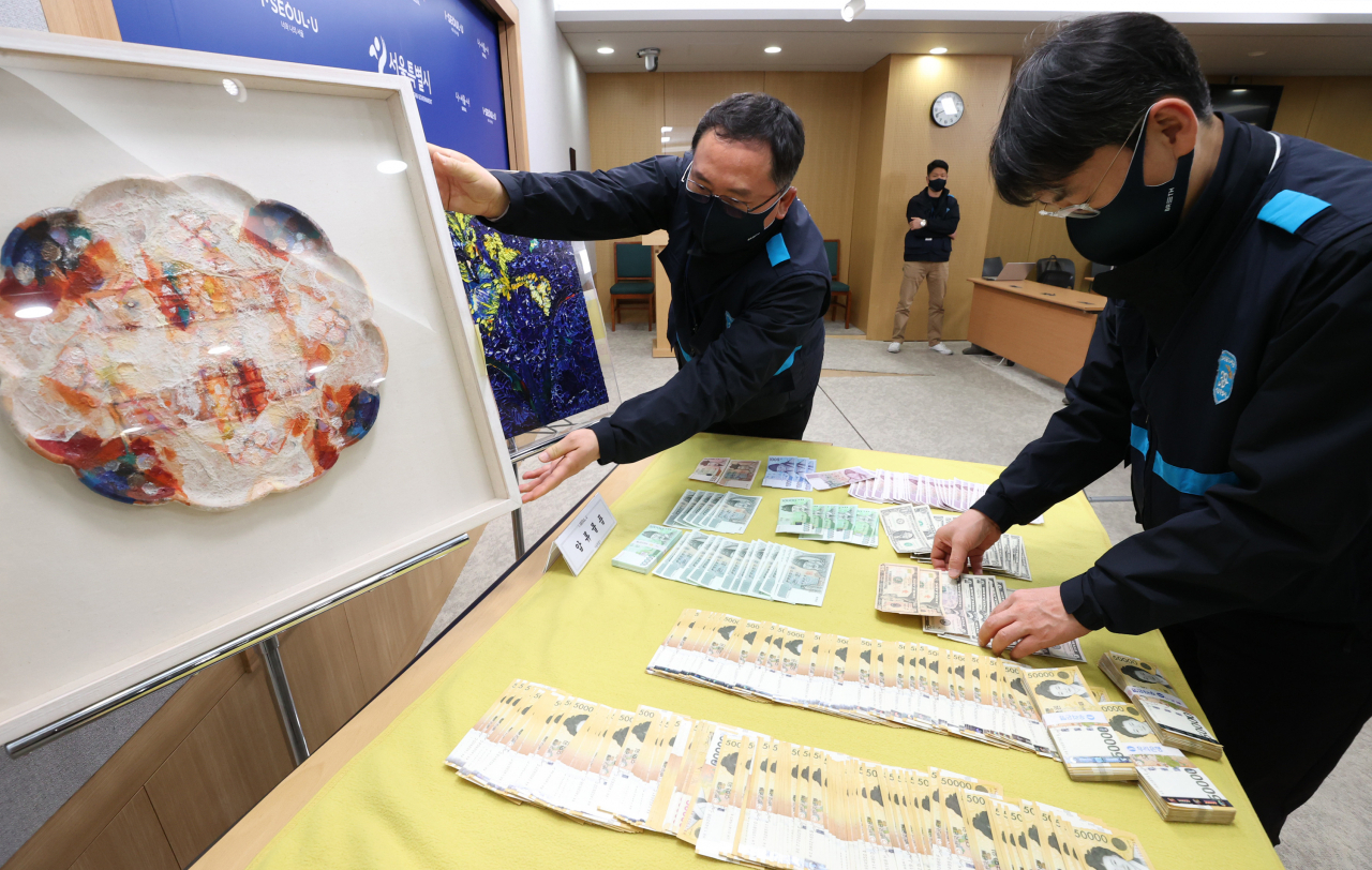 서울시 38세금징수과 직원이 3일 서초구 양재동 최순영 전 신동아그룹 회장 자택에서 압수한 현금과 미술품을 시청 브리핑룸에서 공개하고 있다. 시는 이날 납세자의 날을 맞아 최 전 회장 자택을 수색, 현금 2천687만원과 미술품 등 동산 20점을 압류했다. 최 전 회장은 세금 38억9천만원을 체납하고 있다. 연합뉴스