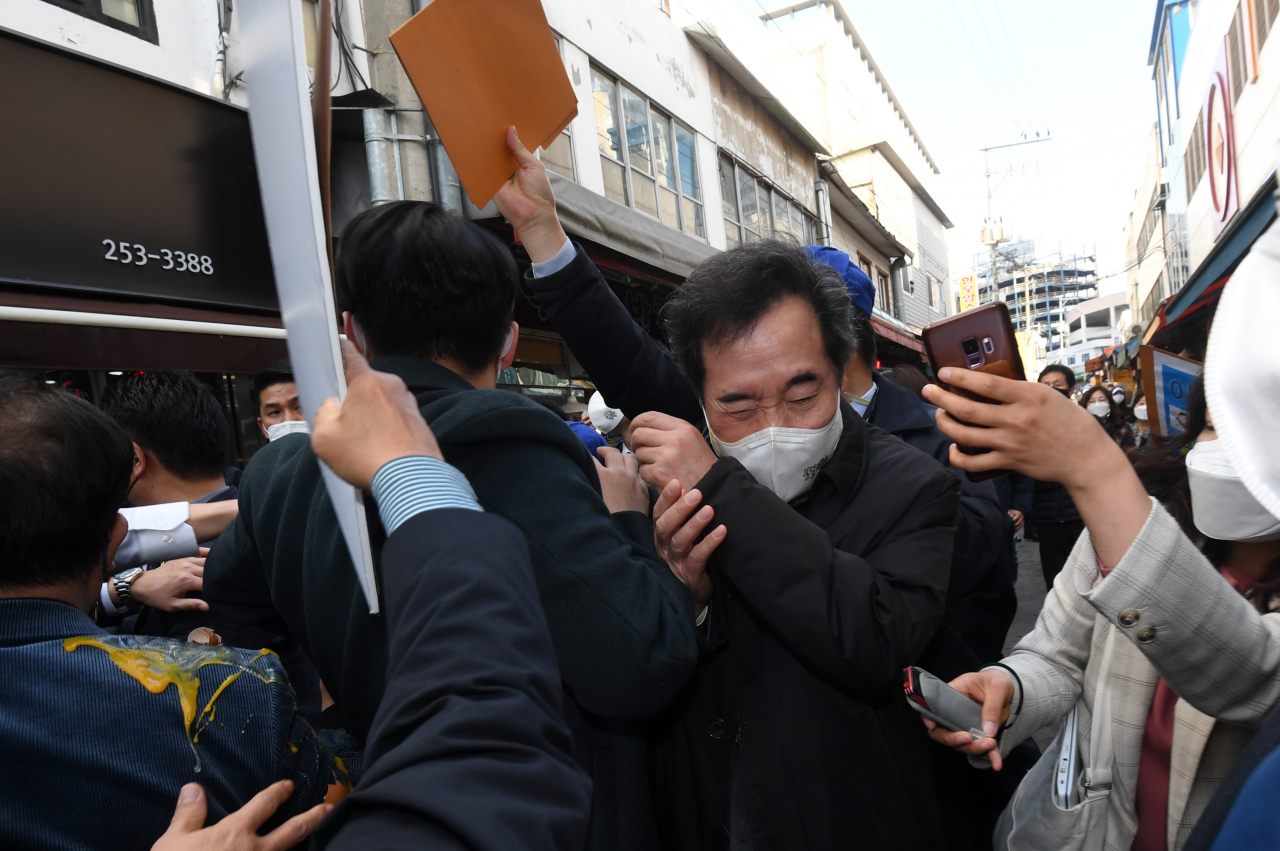 이낙연 더불어민주당 대표가 지난 5일 오후 강원 춘천시 중앙시장을 방문하던 도중 레고랜드 반대 단체 관계자가 달걀을 던져 몸을 피하고 있다. [연합]