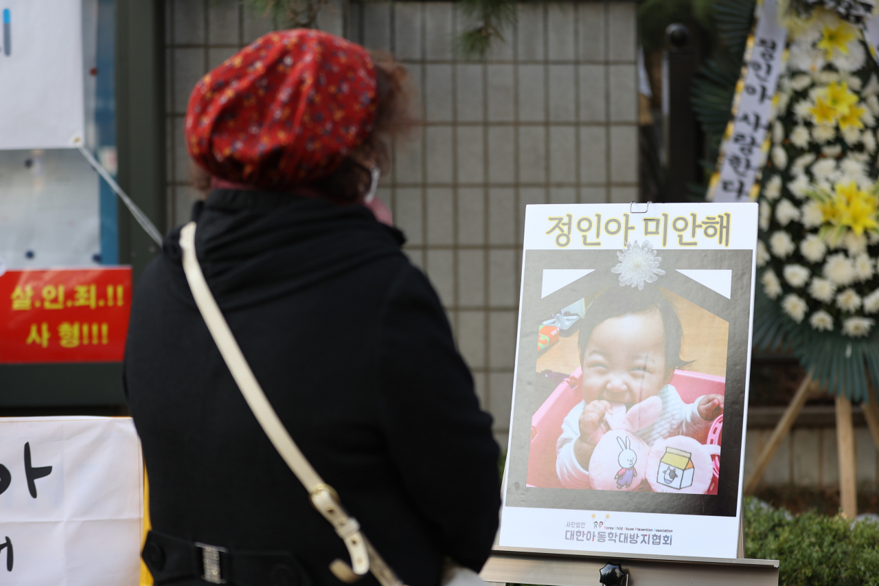 16개월 된 입양 딸 정인이를 학대해 숨지게 한 혐의를 받는 양부모의 3차 공판이 열린 이달 3일 오전 서울 양천구 서울남부지법 앞에서 한 시민이 정인이 사진 앞에서 기도하고 있다. [연합]
