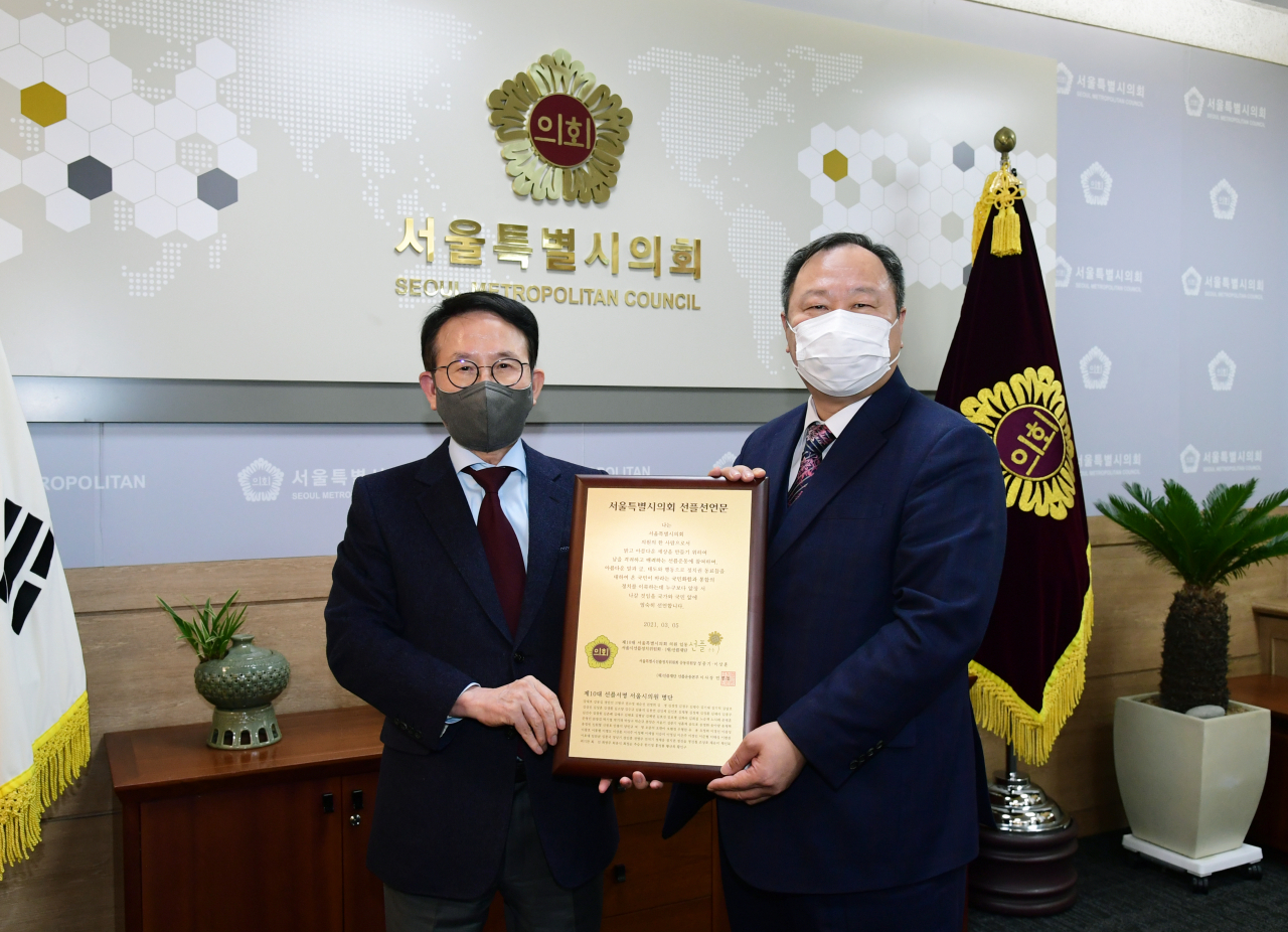 민병철(왼쪽) 선플재단 이사장이 김인호 서울시의회 의장에게 선플서명에 참여한 서울시의원 108명의 명단이 새겨진 동판을 전달하고 있다.
