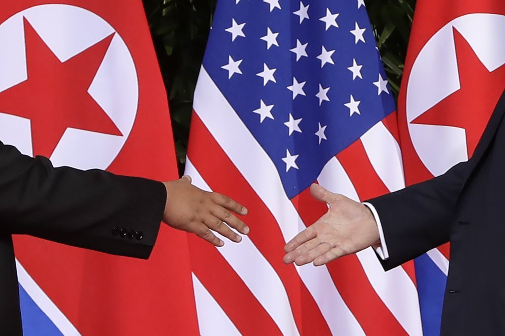 US President Donald Trump, right, reaches to shakes hands with North Korea leader Kim Jong Un at the Capella resort on Sentosa Island Tuesday, June 12, 2018 in Singapore. (AP-Yonhap)