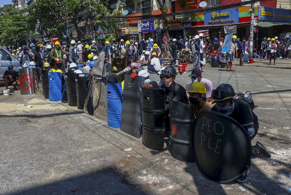 Anti-coup protesters take cover behind makeshift shields during a demonstration in Yangon, Myanmar Thursday, March 4, 2021. (AP-Yonhap)