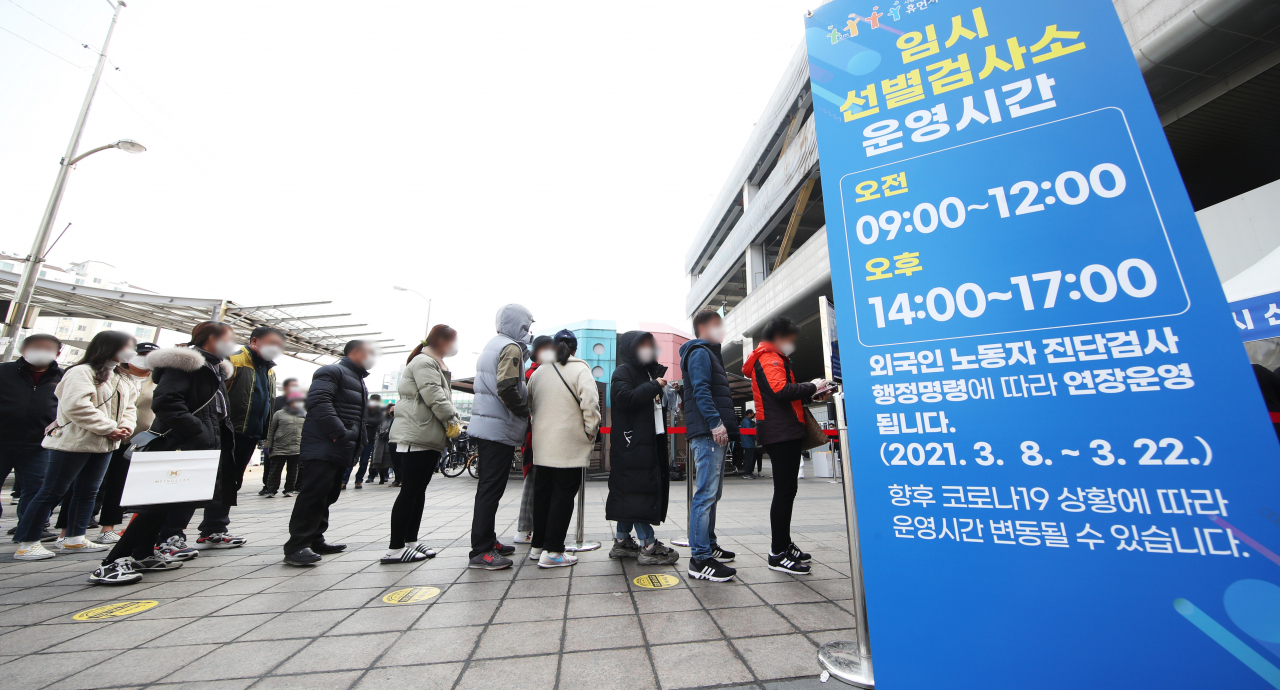 14일 오전 경기도 수원역 광장에 설치된 코로나19 임시선별진료소에 시민들과 경기도 내 외국인 근로자 코로나19 전수검사 행정명령에 따라 검사를 받으러 온 외국인 근로자들이 길게 줄을 서 있다. [연합]