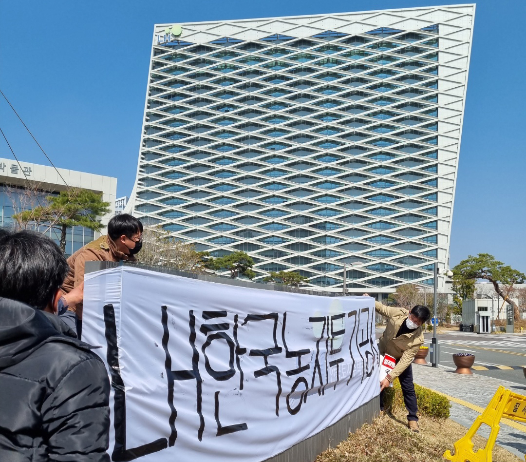 전국농민회총연맹 부산경남연맹 소속 농민들이 지난 8일 경남 진주시 충무공동 한국토지주택공사(LH) 본사 정문 앞 표지석에 'LH 한국농지투기공사'라고 쓴 현수막을 둘러치는 퍼포먼스를 벌이고 있다. [연합]