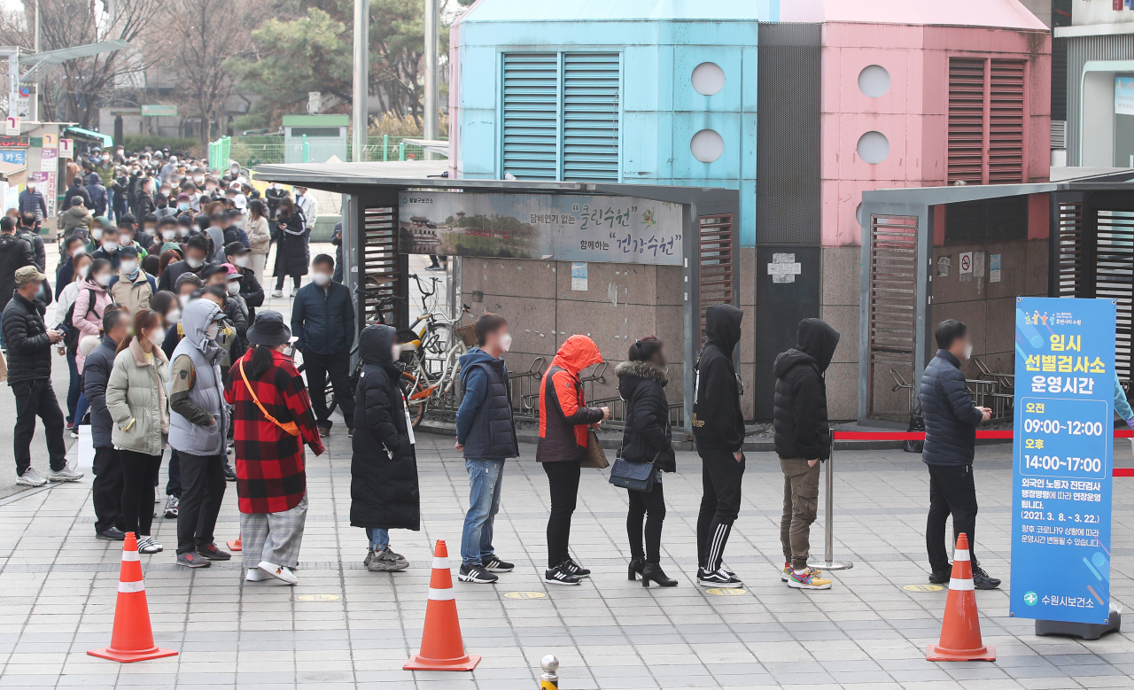 지난 14일 오전 경기도 수원역 광장에 설치된 코로나19 임시선별진료소에 시민들과 경기도 내 외국인 근로자 코로나19 전수검사 행정명령에 따라 검사를 받으러 온 외국인 근로자들이 길게 줄을 서 있다. [연합]