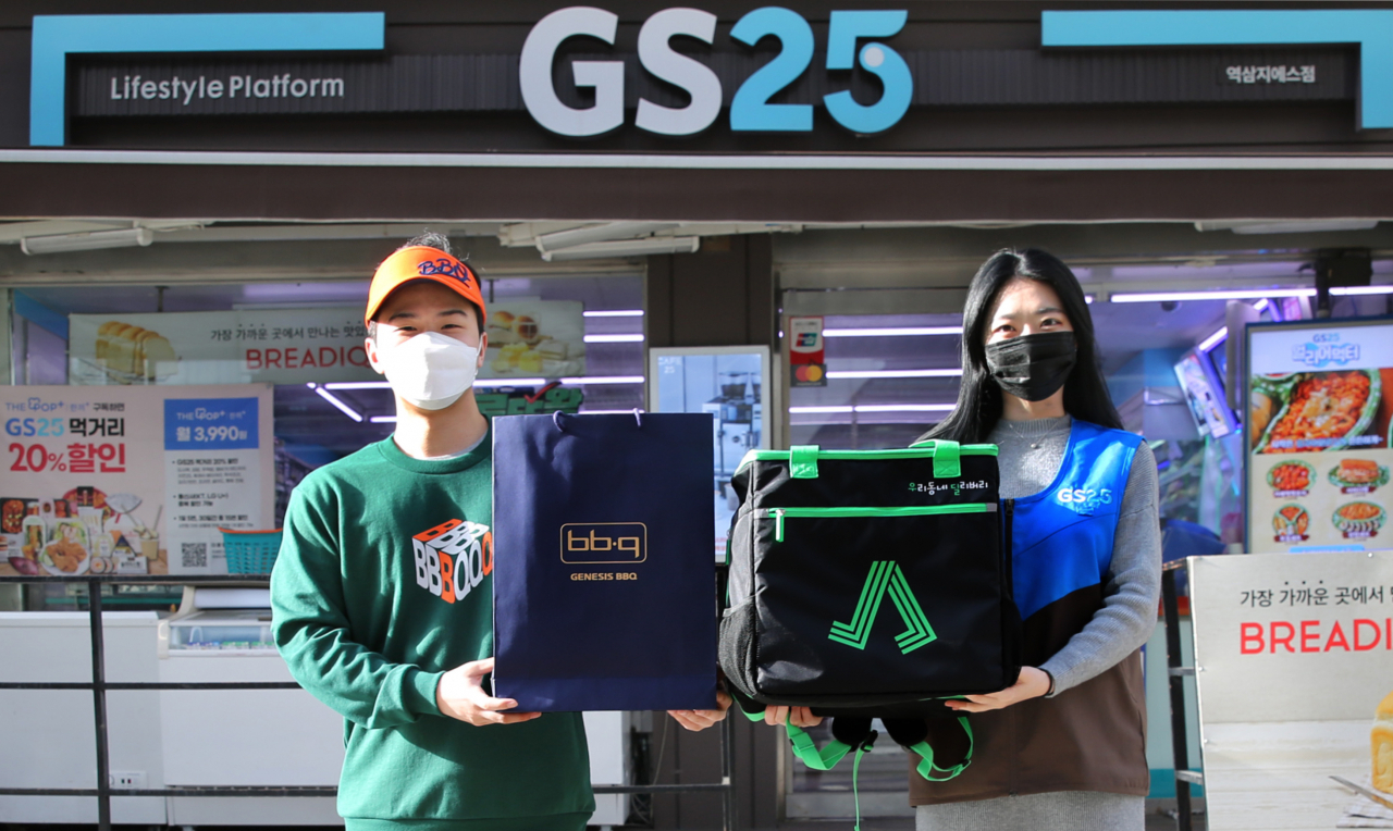 GS25 앞에서 모델들이 GS25와 BBQ 유니폼을 입고 배달 서비스를 알리고 있다. [GS25 제공]