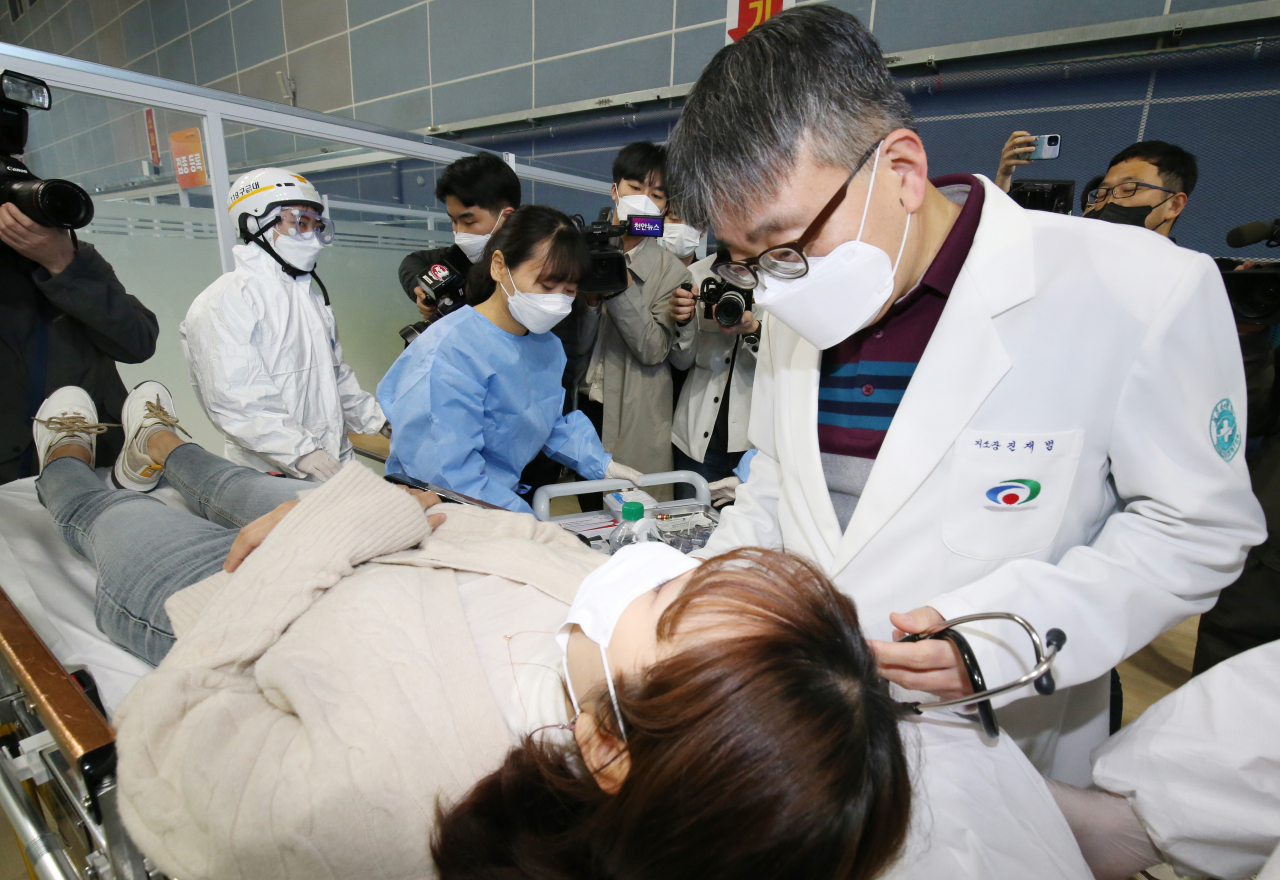 지난 17일 오전 충남 천안시 서북구 실내테니스장에 마련된 예방접종센터에서 실시된 지역 예방접종센터 모의훈련에서 의료진이 이상반응 발생으로 응급처치실로 이송된 접종대상자를 진찰하고 있다. [연합]