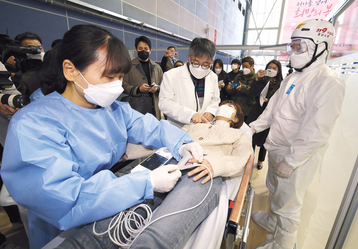 지난 17일 오전 충남 천안시 서북구 실내테니스장에 마련된 예방접종센터에서 실시된 지역 예방접종센터 모의훈련에서 의료진이 이상반응 발생으로 응급처치실에 이송된 접종대상자를 진찰하고 있다. [연합]