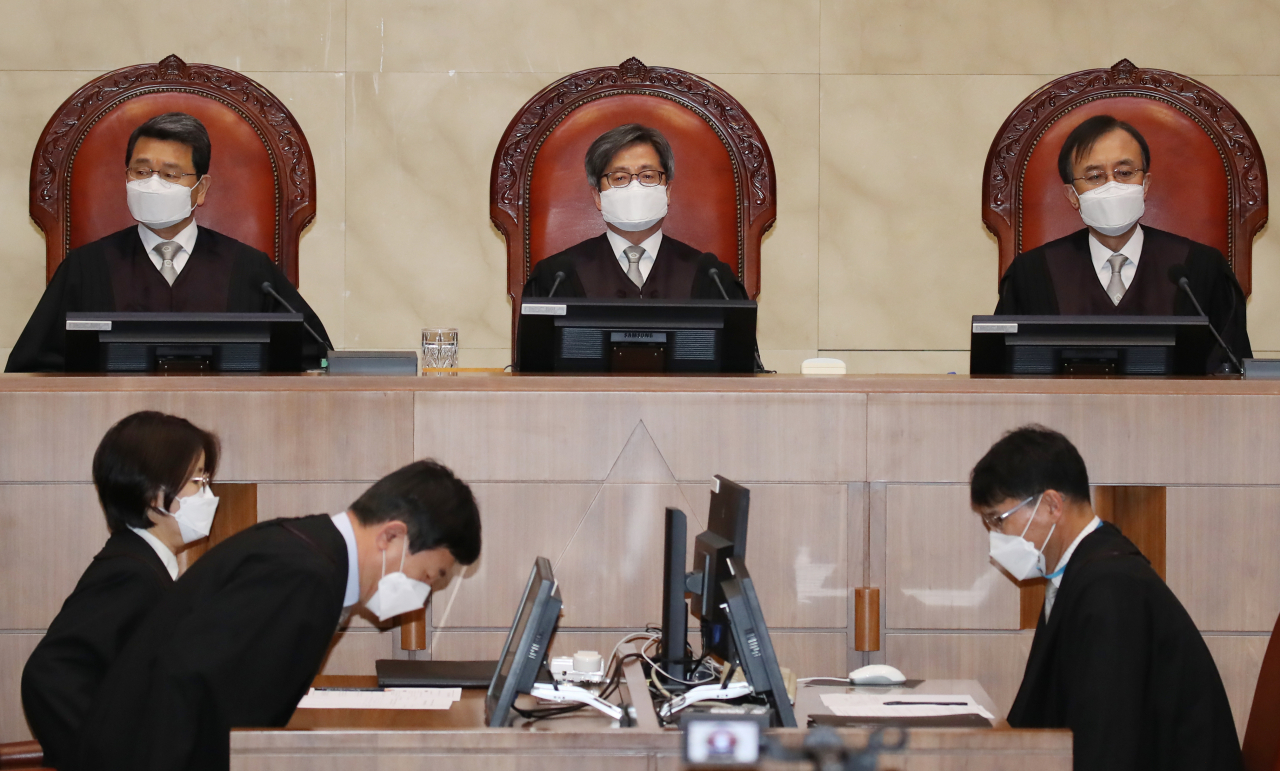 김명수 대법원장(가운데)을 비롯한 대법관들이 18일 오후 서울 서초구 대법원에서 열린 육아휴직급여 부지급 등 처분 취소 전원합의체 선고를 위해 대법정에 입장해 자리에 앉아 있다. [연합]