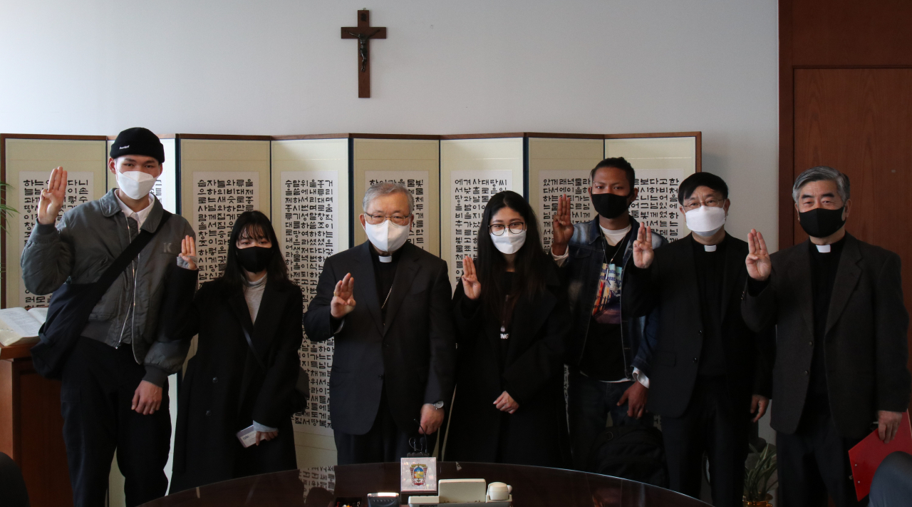 천주교 서울대교구장 염수정 추기경과 미얀마 청년들이 만나 세 손가락 경례로 기념사진을 찍고 있다. 왼쪽부터 서뚜카오 씨, 한수진 씨, 염수정 추기경, 진마툰 씨, 무온먁쪄 씨, 천주교 서울대교구 대변인 허영엽 신부, 가톨릭 영성심리상담소 소장 홍성남 신부. 서울대교구 제공