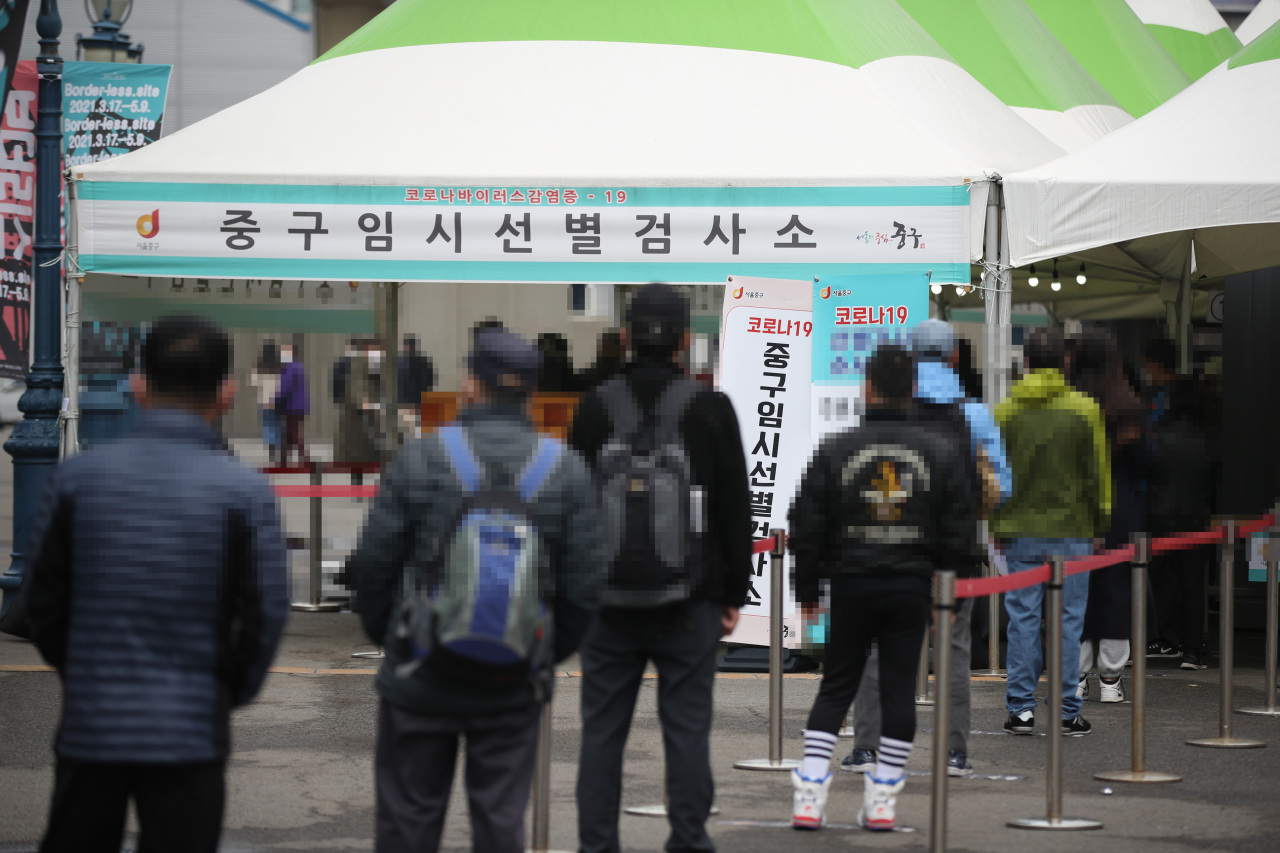 People wait in line by a temporary testing center in Jung-gu, central Seoul, on Sunday to get checked for COVID-19. (Yonhap)