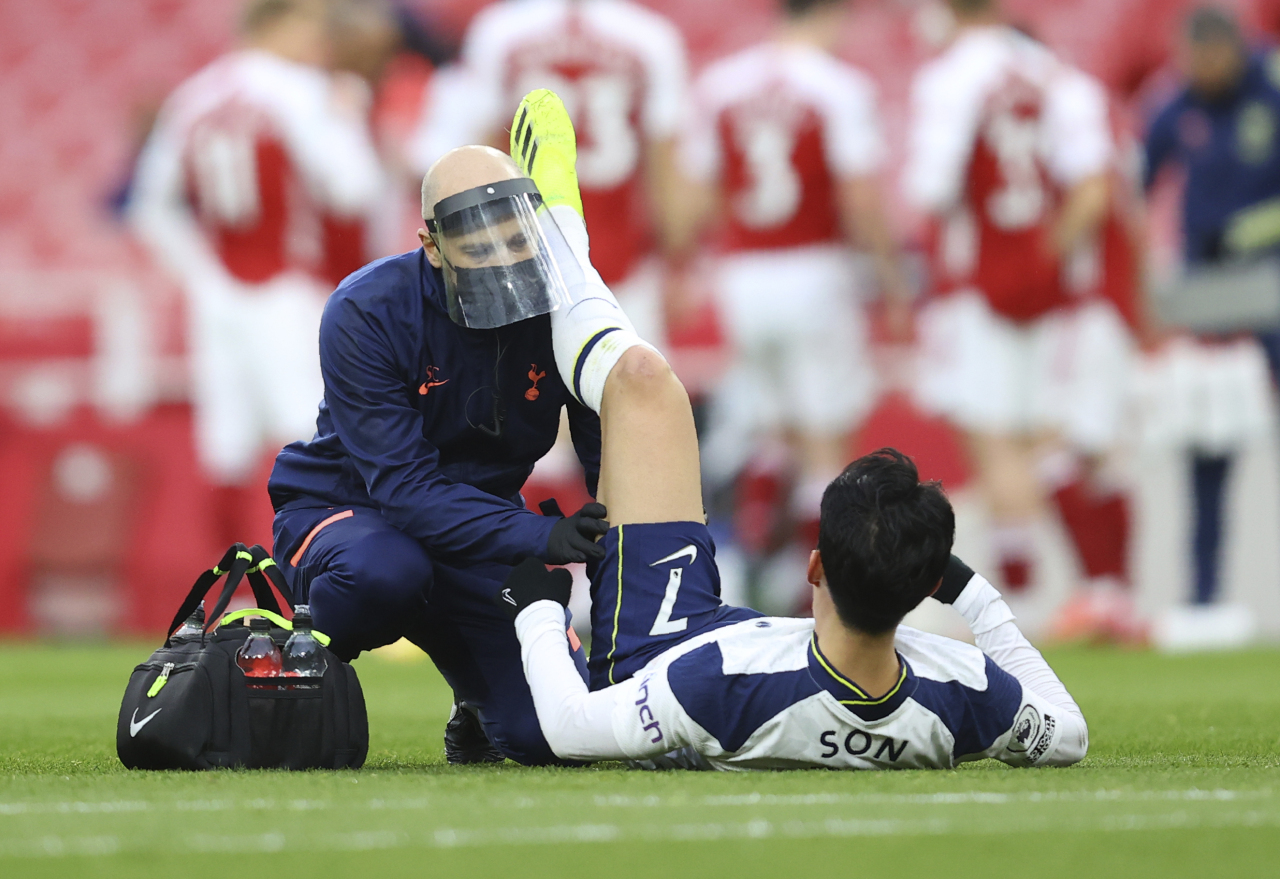 Tottenham's Son Heung-min receives medical attention during the English Premier League soccer match between Arsenal and Tottenham Hotspur at the Emirates stadium in London, England on March 14. (AP-Yonhap)